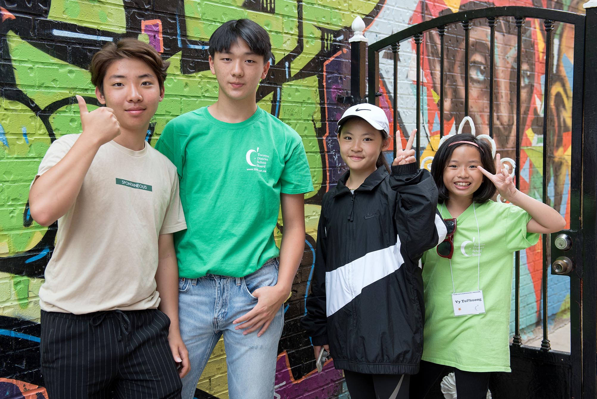 Students posing in front of graffiti wall Open Gallery